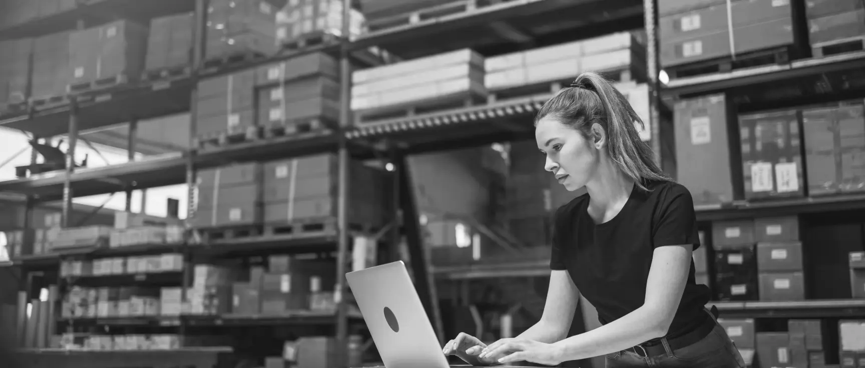 Woman working on a laptop inside a warehouse